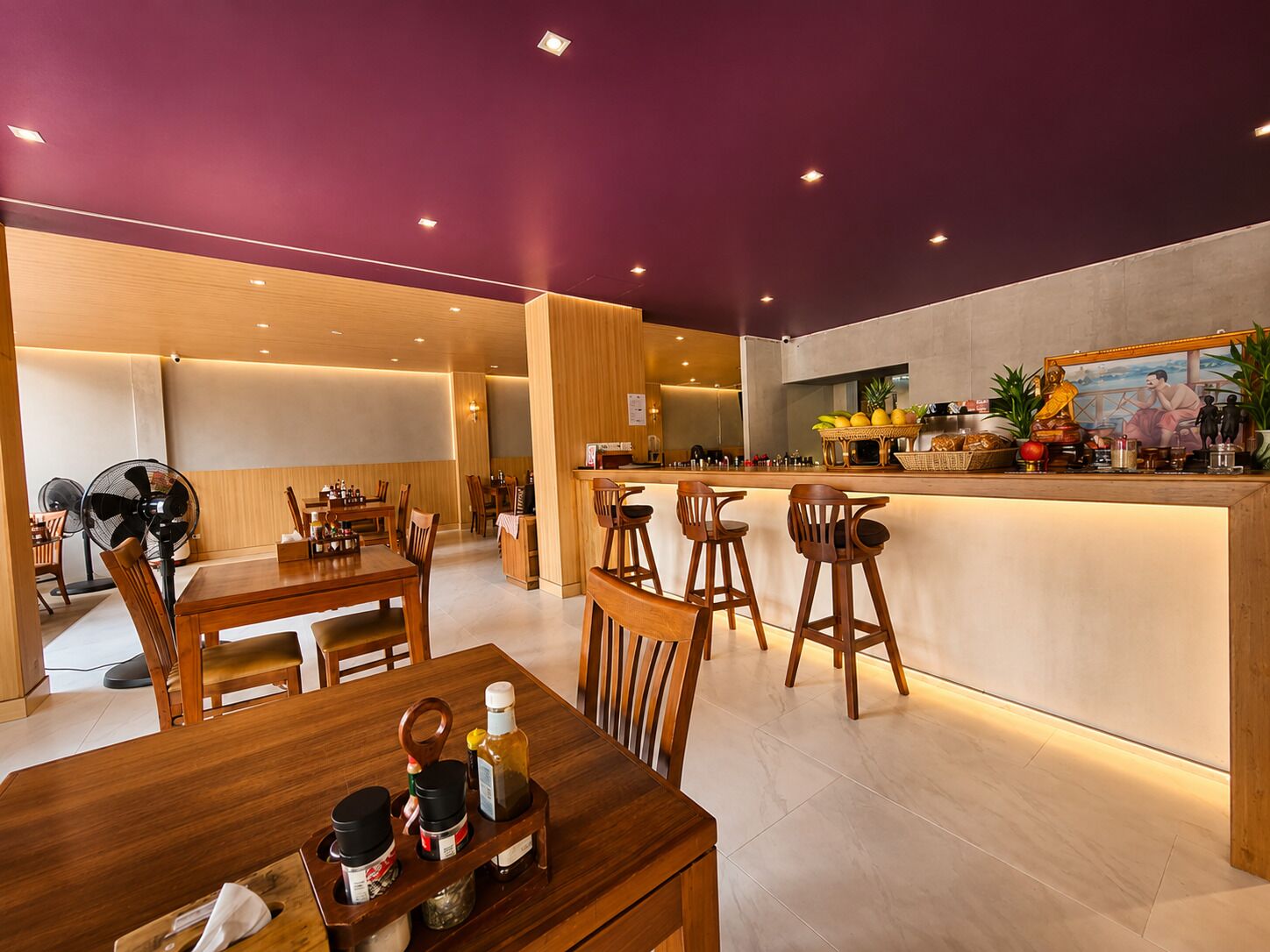 A restaurant with wooden tables and chairs, a bar area, and a ceiling with recessed lighting.