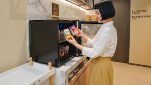 Uma pessoa escolhendo bebidas em um refrigerador em um ambiente de hotel.