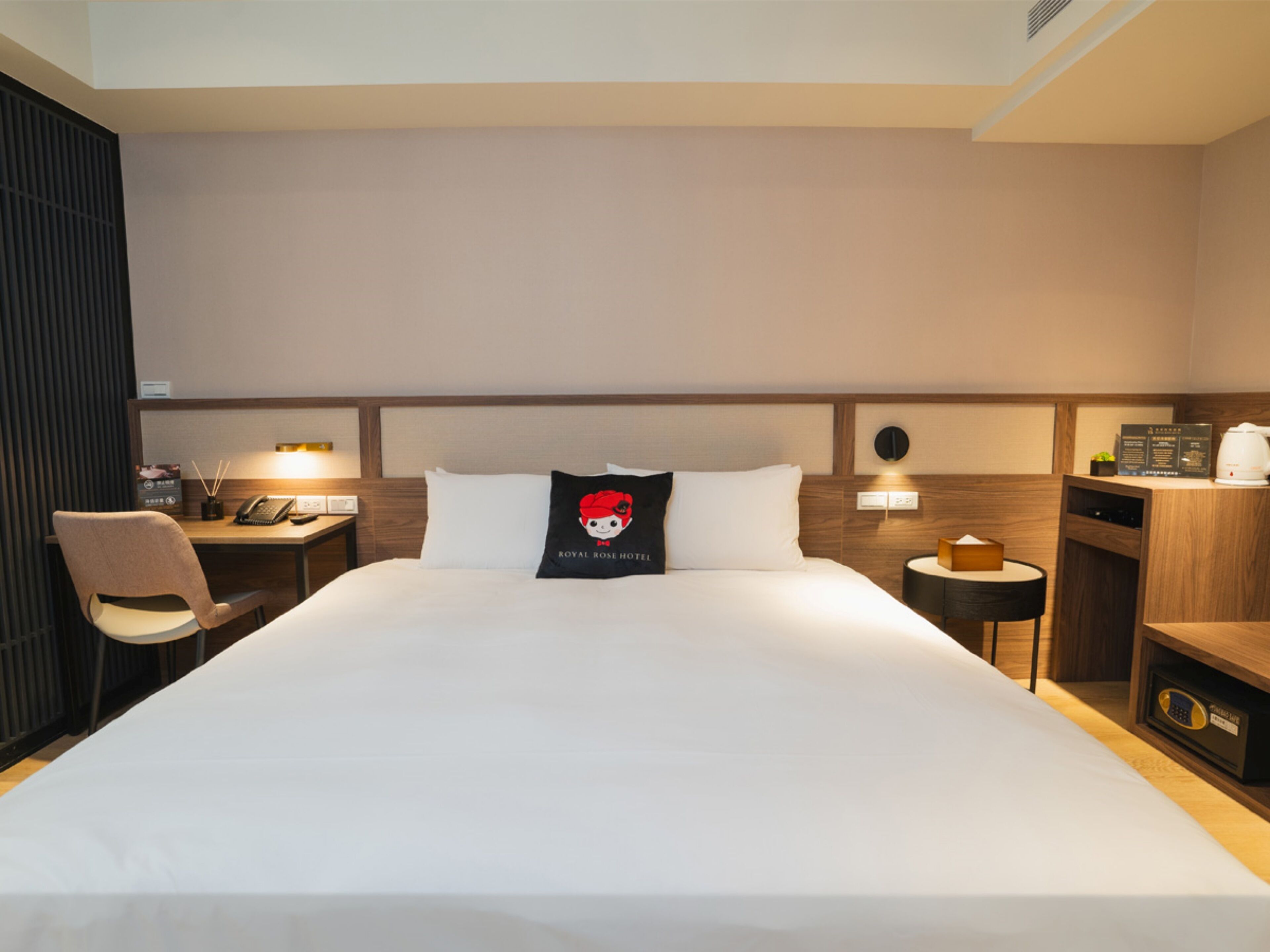 Ein Hotelzimmer mit einem großen Bett, einem Schreibtisch, einem Sessel, einem Nachttisch und einem kleinen Tisch mit einer Lampe.