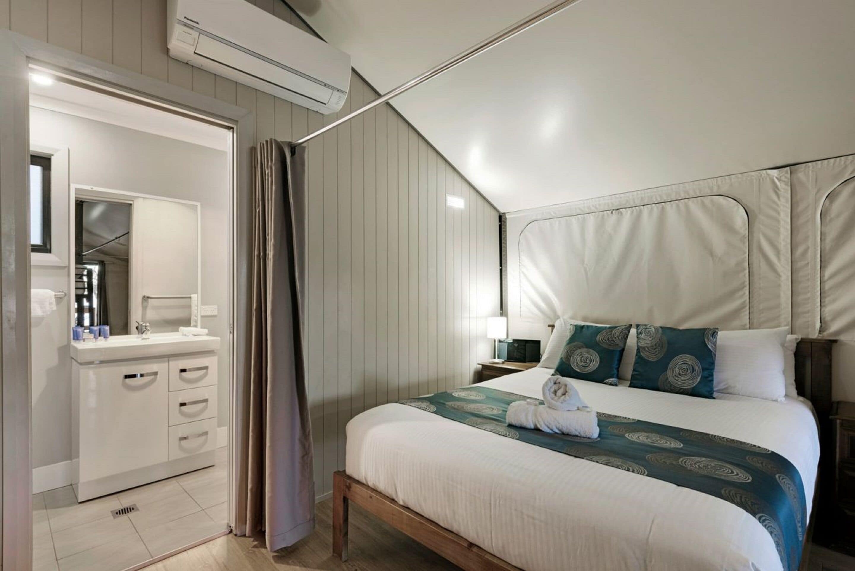 A bedroom with a bed, bedside table, lamp, and a window with curtains.