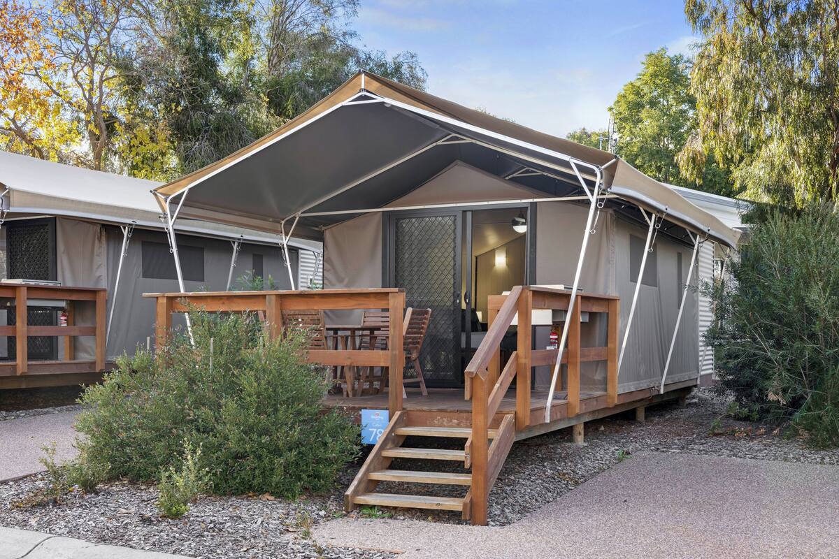 A mobile home with a covered porch, a wooden staircase, and a small garden area.