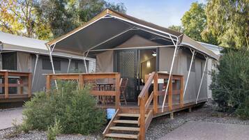 A mobile home with a covered porch, a wooden staircase, and a small garden area.