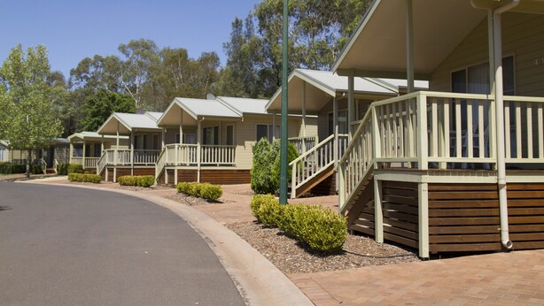 A row of single-story cabins with front porches and steps leading to the entrance. - Discovery Parks - Dubbo (Dubbo)
