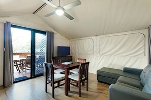 A tented room with a dining table, chairs, a sofa, and a ceiling fan.