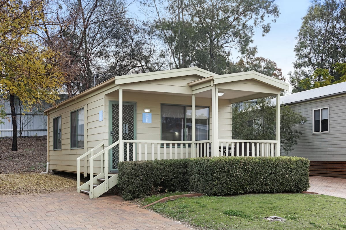A single-story mobile home with a covered porch and a small staircase leading to the entrance.