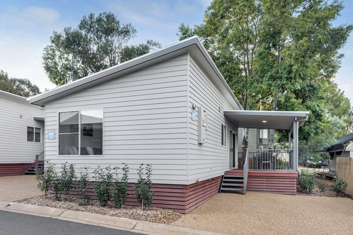 A single-story mobile home with a covered porch and a small front yard.