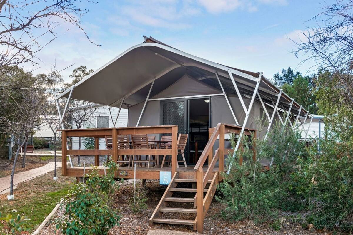 A tented accommodation with a wooden deck and stairs leading to the entrance.