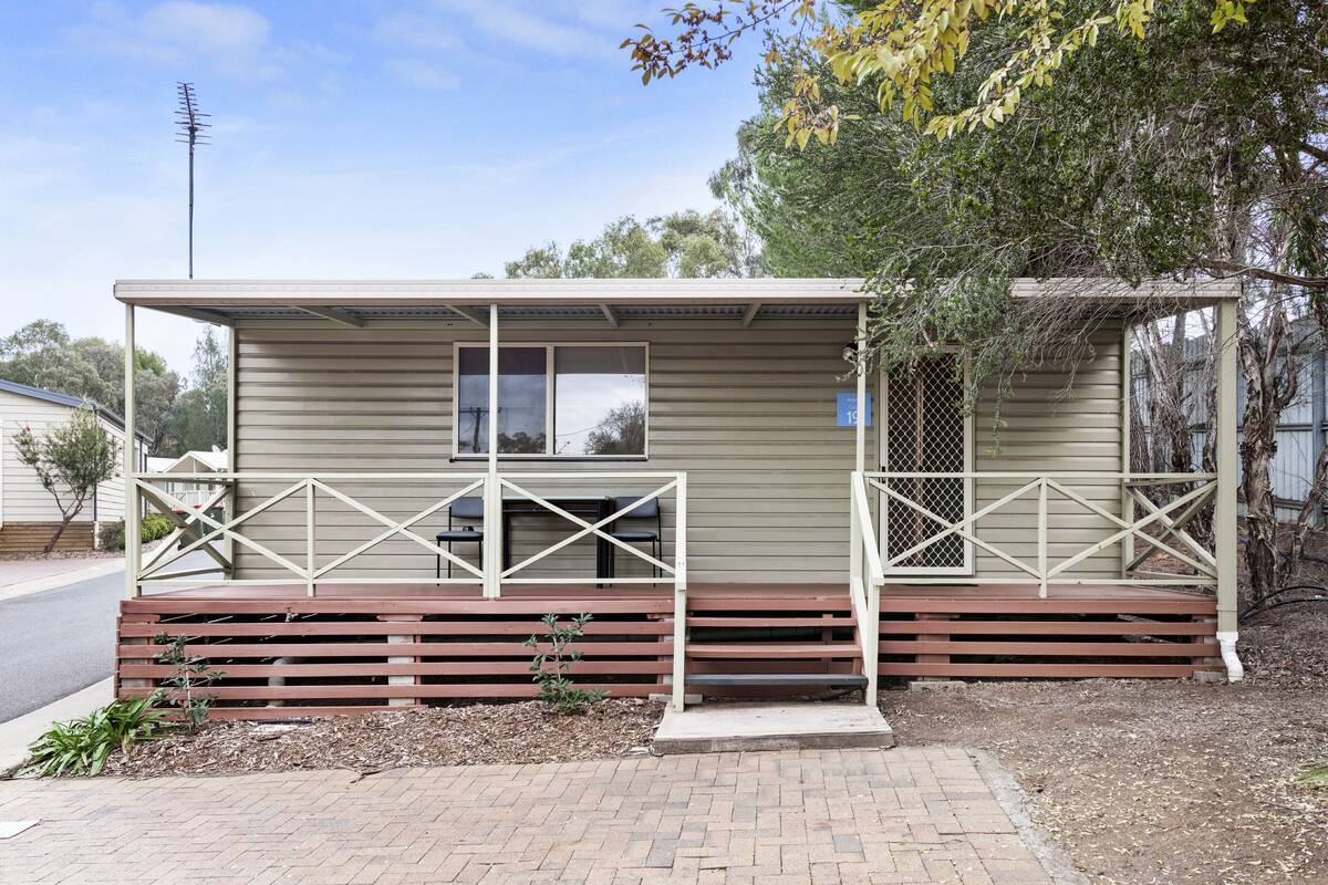 A small, single-story cabin with a covered porch and a small front yard.