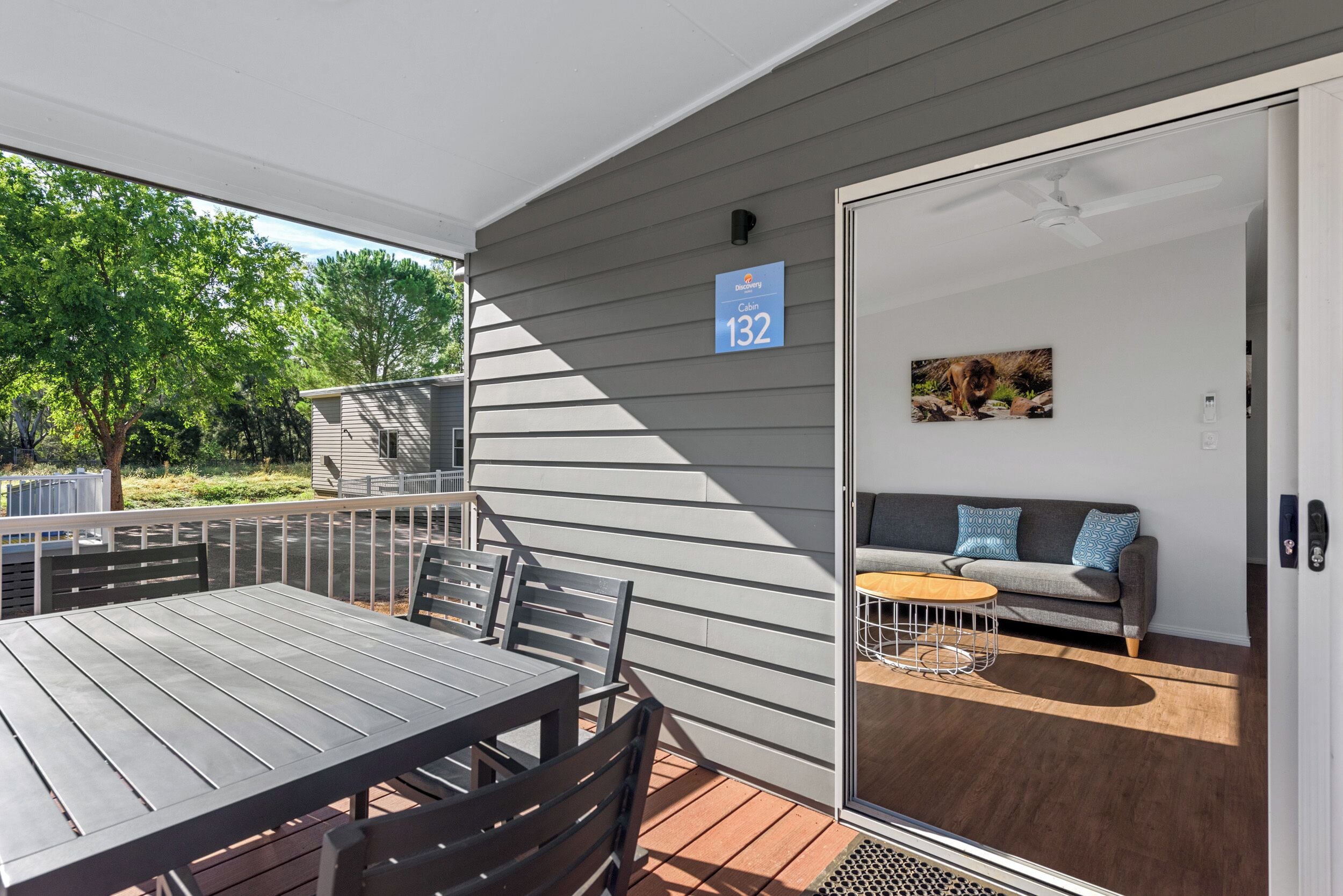 A balcony with a table and chairs, a sofa, and a sliding door to a room with a painting.