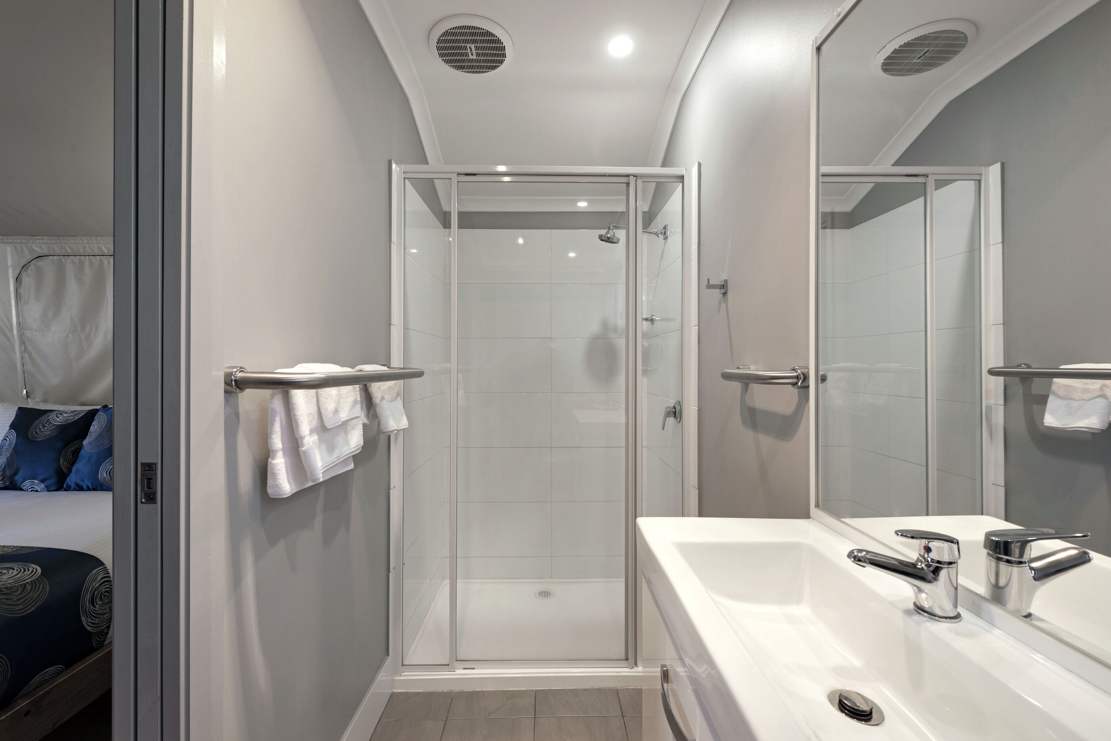 A modern bathroom with a glass-enclosed shower, a large white bathtub, and a mirror.
