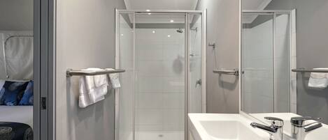 A modern bathroom with a glass-enclosed shower, a large white bathtub, and a mirror.