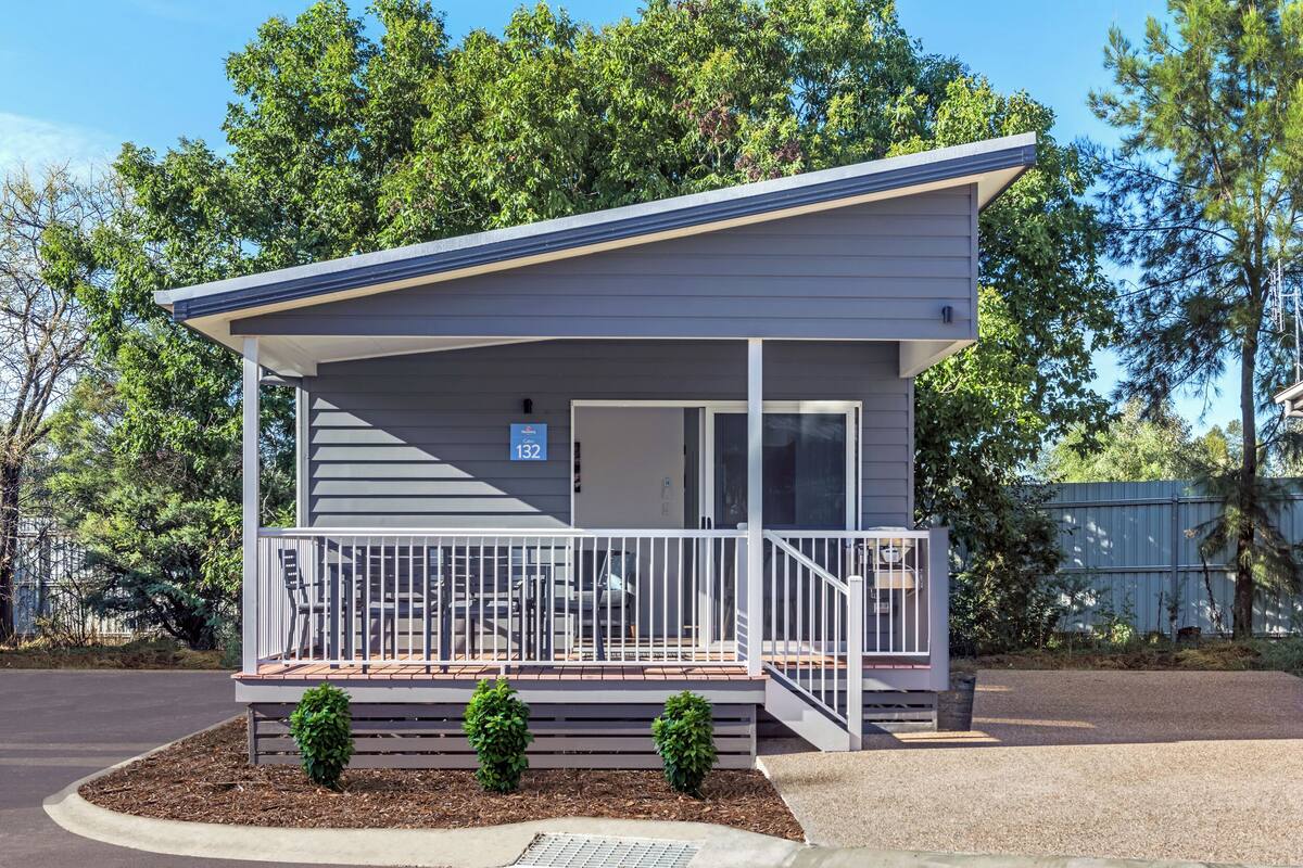 A single-story motel with a covered porch, a small patio, and a number '132' sign.