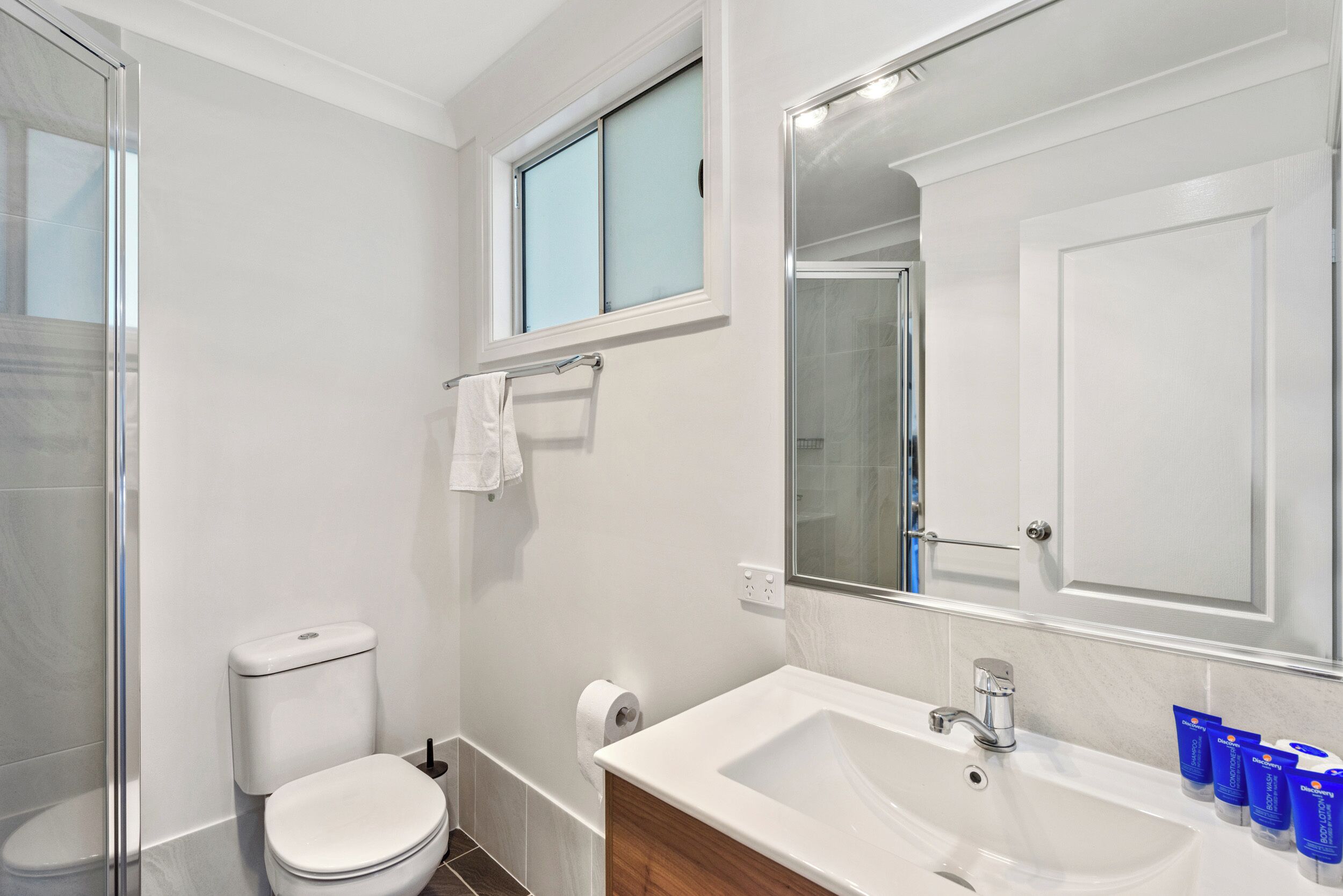 Un baño moderno con inodoro, lavamanos y ducha.