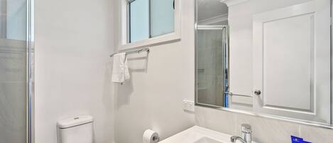 Un baño moderno con inodoro, lavamanos y ducha.