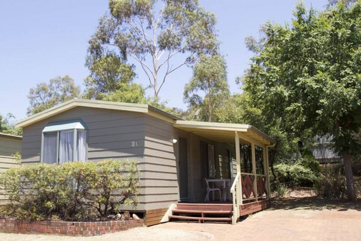 A single-story mobile home with a porch and a brick foundation.