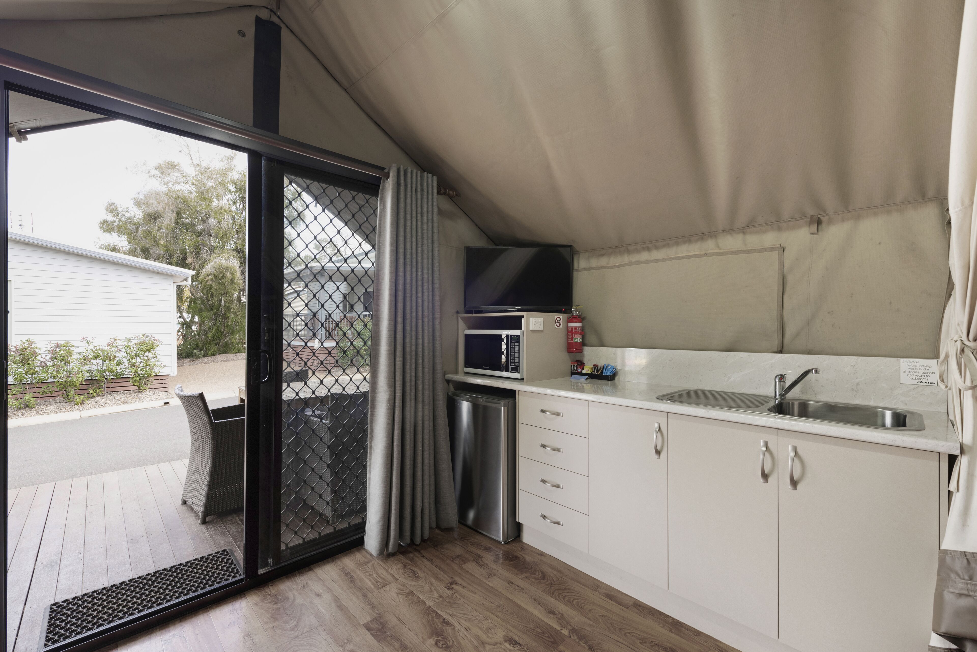 A compact kitchen with a microwave, sink, and storage cabinets.