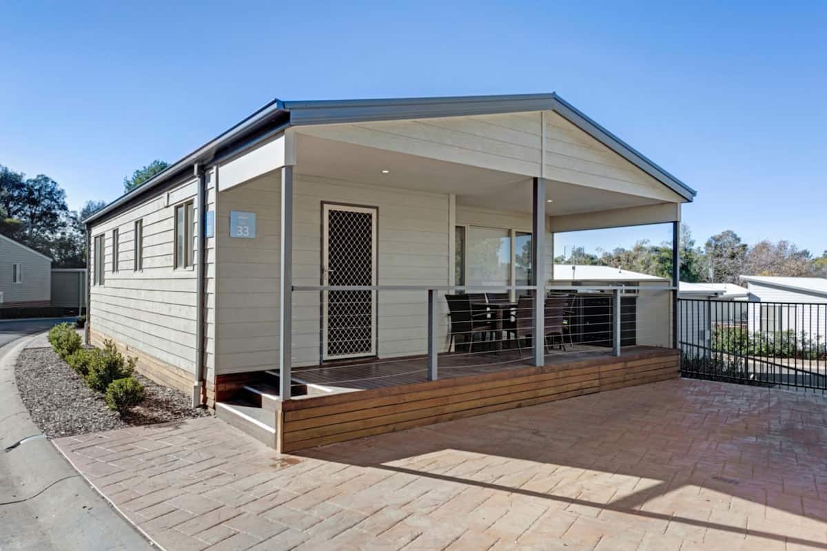 A single-story house with a covered porch, a number 33 sign, and a fenced backyard.