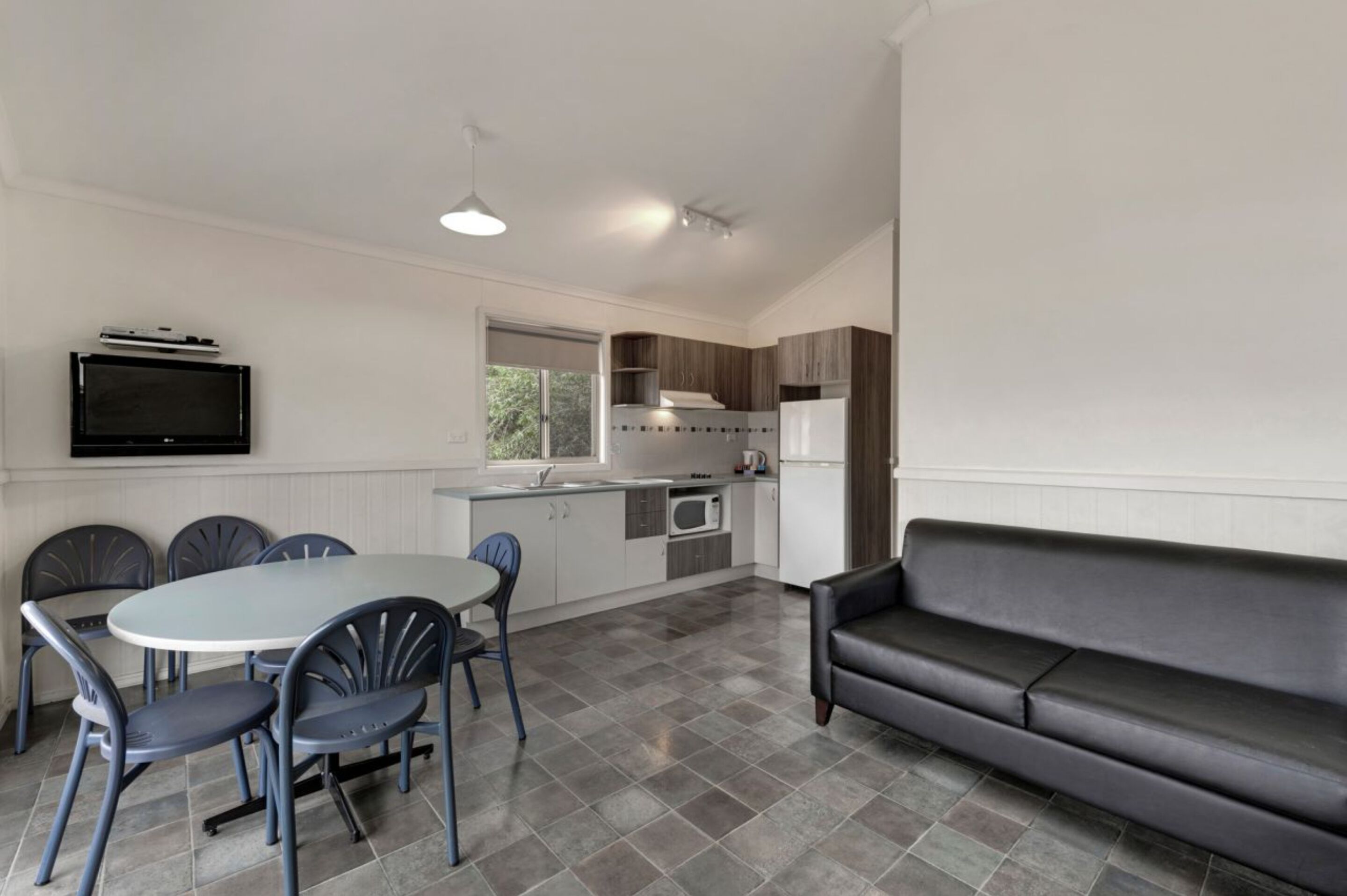 A modern kitchen with a dining area, a flat-screen TV, and a sofa.