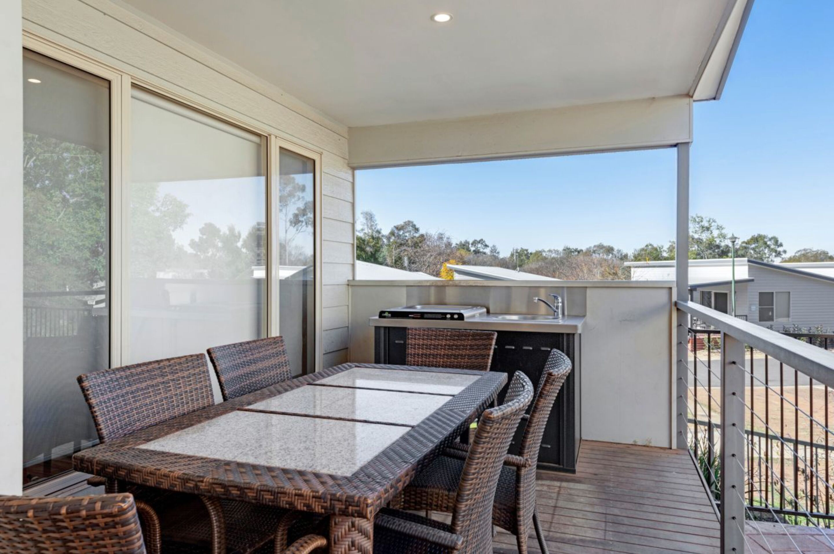 Un balcon avec une table et des chaises pour prendre les repas, un petit coin cuisine et une vue sur les environs.