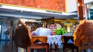 Un vestíbulo con techo de madera, un candelabro, un mural grande en la pared y una mesa de recepción.