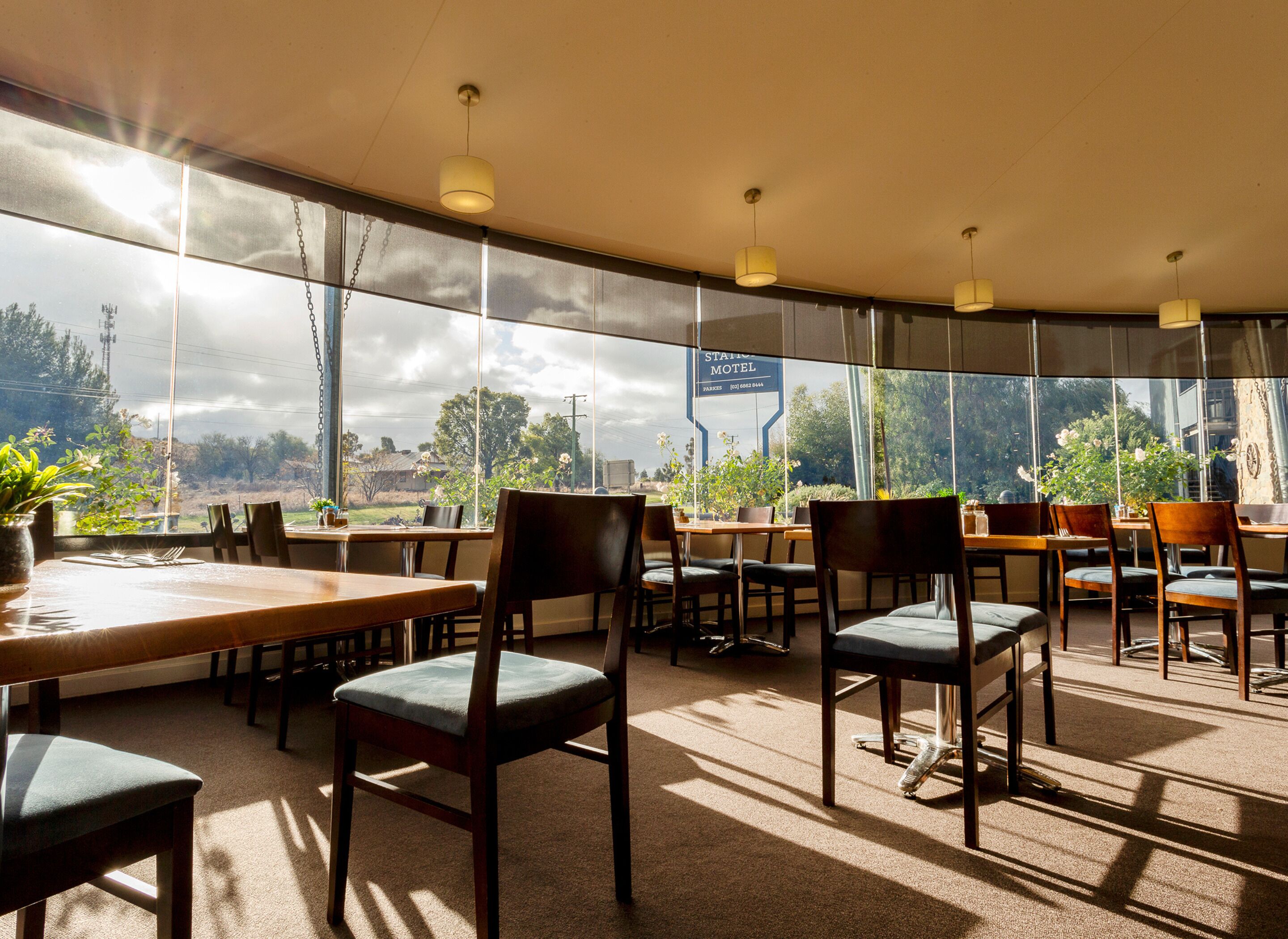 A spacious dining area with large windows, multiple tables, and chairs.