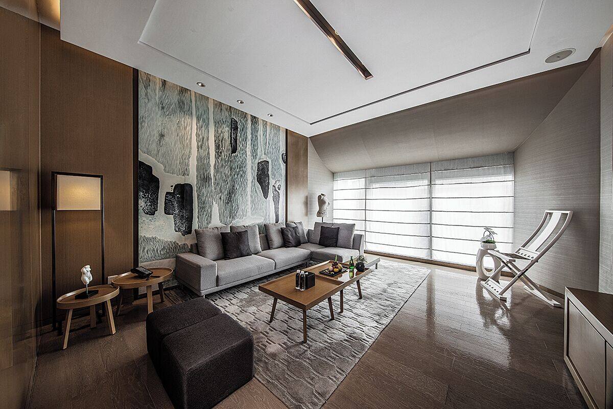 A modern living room with a grey sofa, a coffee table, and a large abstract painting on the wall.