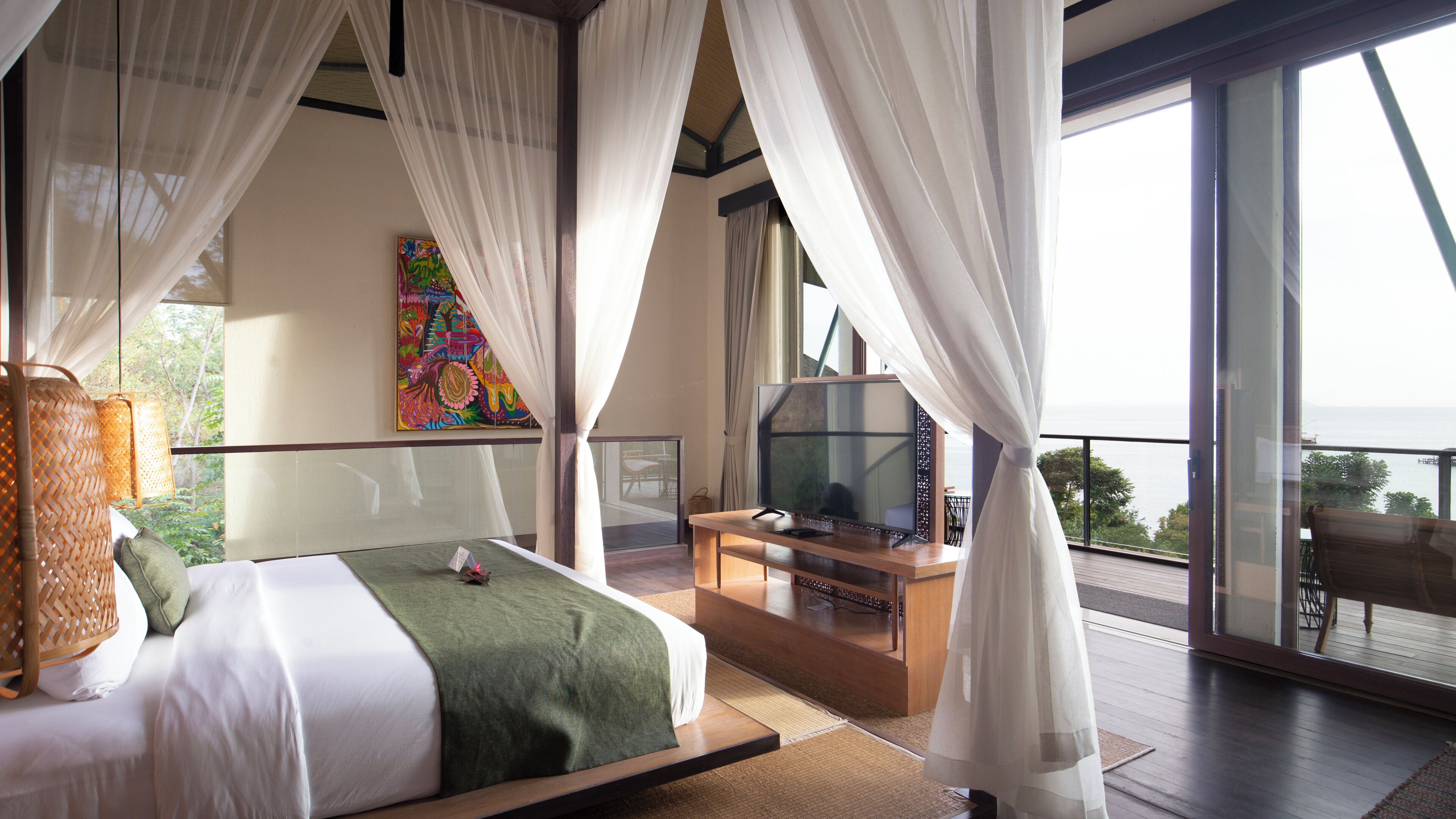 Un dormitorio con cama, televisión y vista al océano.