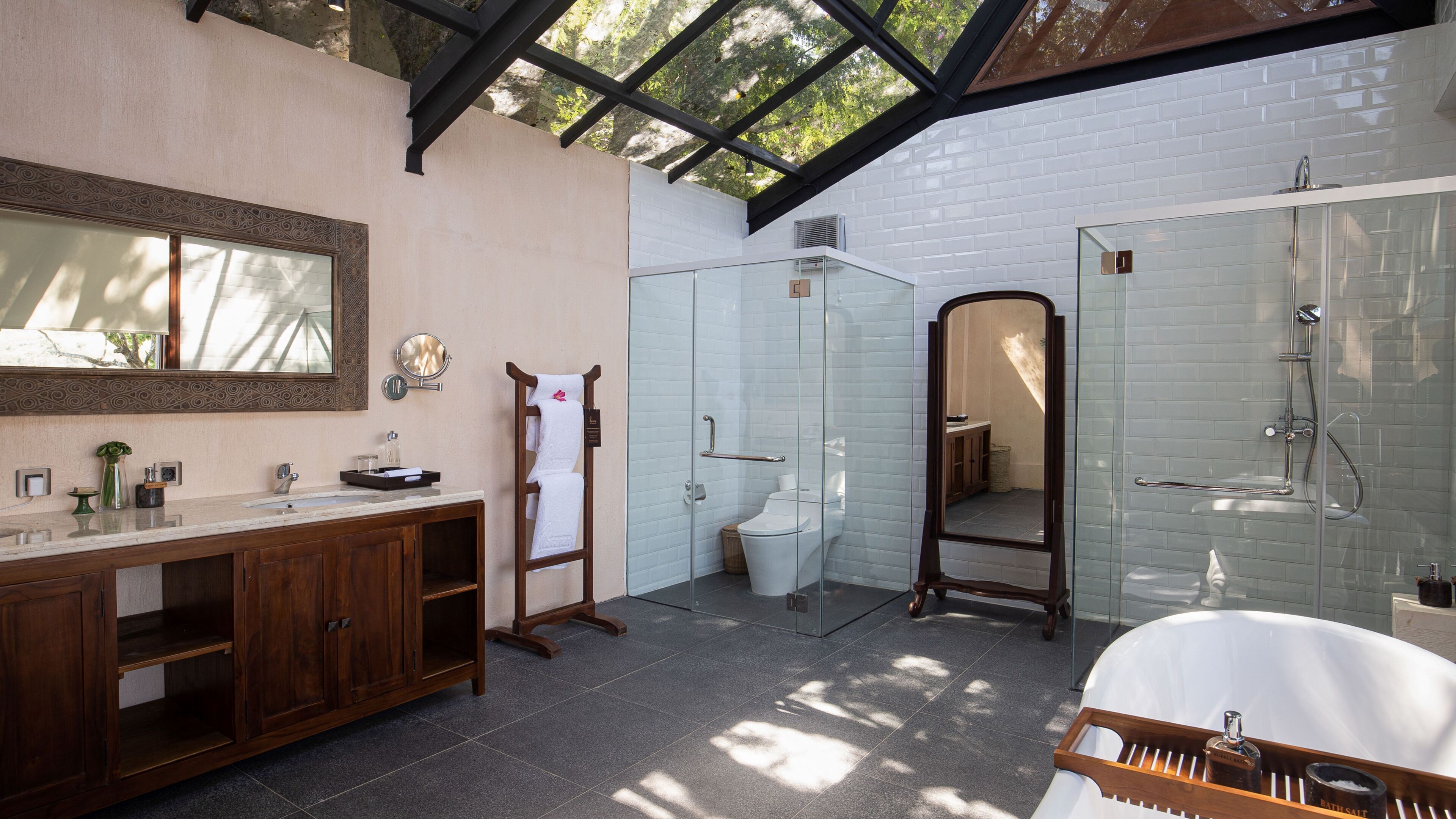 Un baño moderno con cabina de ducha de vidrio, una bañera independiente y un tocador con espejo.