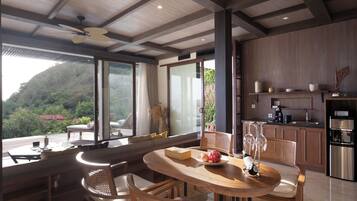 Una cocina moderna con horno integrado, un comedor con mesa y sillas redondas, y ventanas grandes que ofrecen vistas al exterior.
