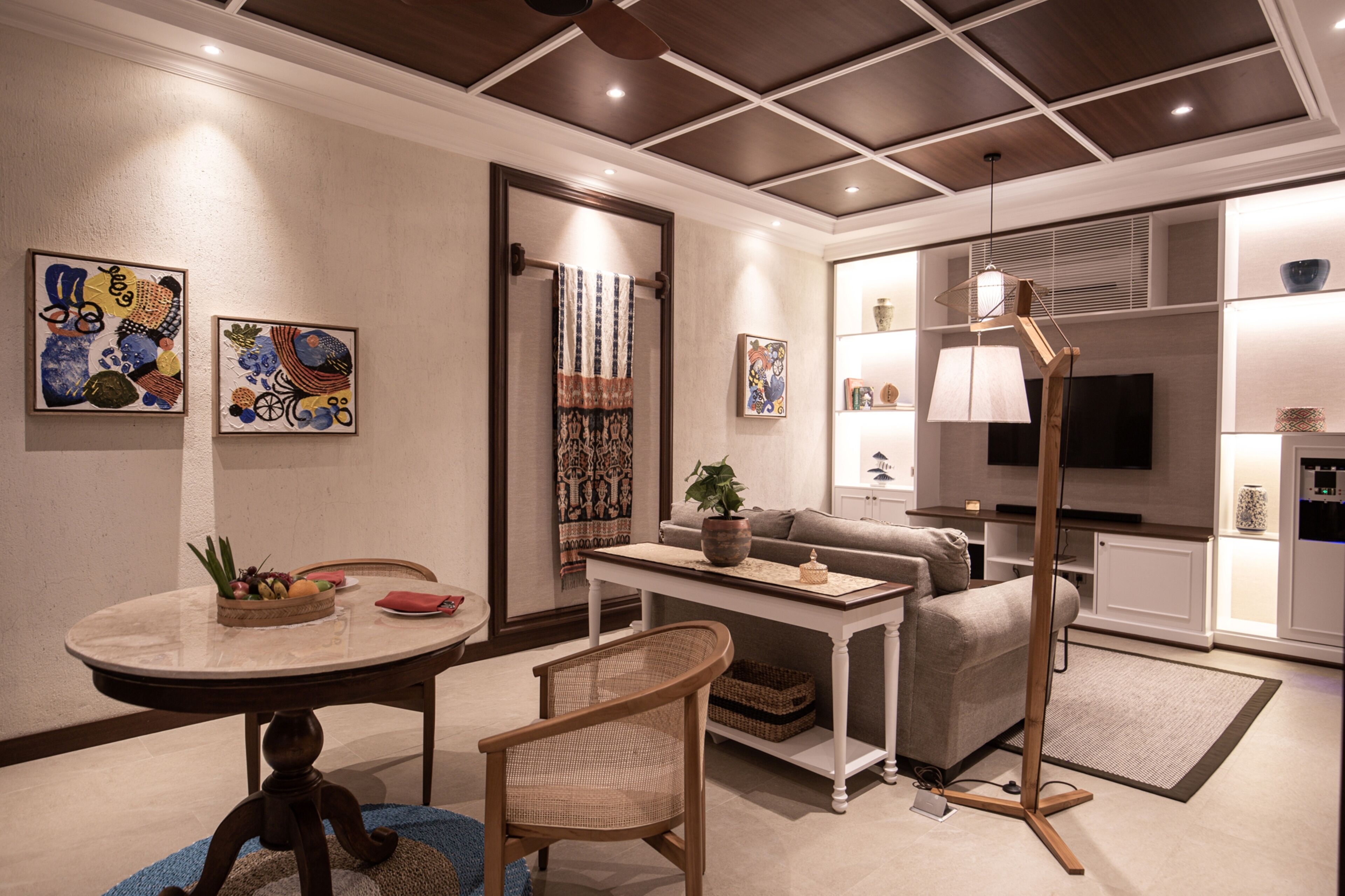A modern living room with a sofa, coffee table, and a television. There are decorative items on the walls and a plant on the coffee table.