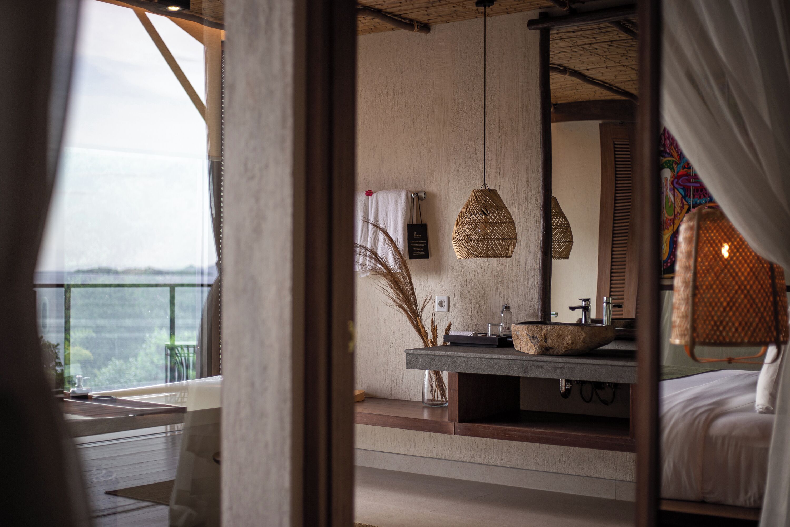A modern bathroom with a large mirror, a stone sink, and a hanging light fixture.