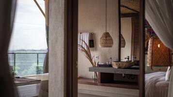 A modern bathroom with a large mirror, a stone sink, and a hanging light fixture.