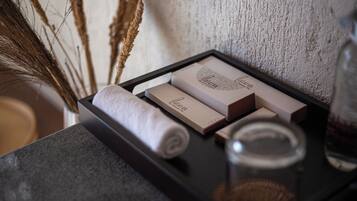 Una bandeja con una toalla enrollada, un tarro de vidrio y dos cajas con la inscripción 'Algar' y 'Laguardia' sobre un fondo de pared texturizada.
