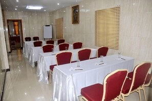 A conference room with tables and chairs, a whiteboard, and a painting on the wall.