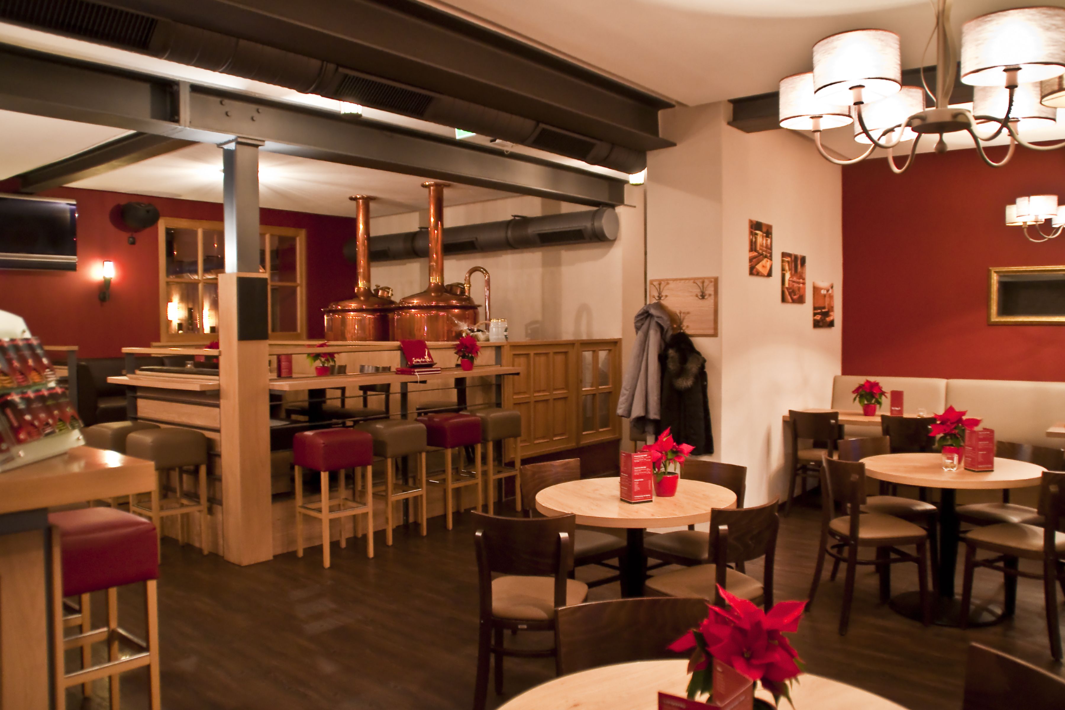 A restaurant with round tables, wooden chairs, and red walls.