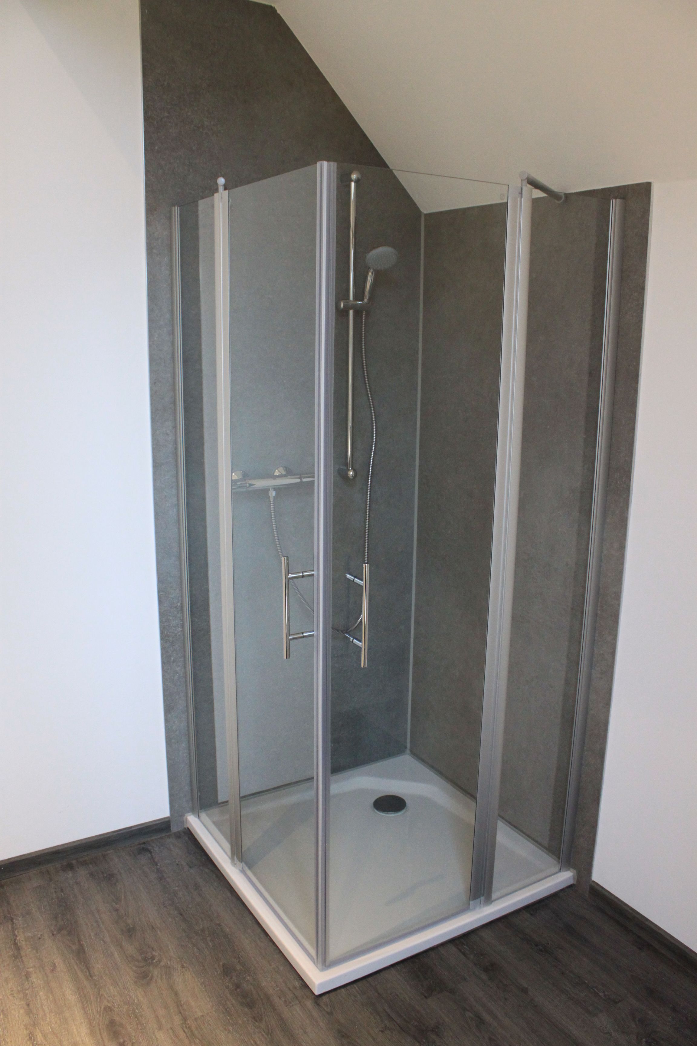 Cabina doccia con pareti in vetro, soffione e pannello comandi.