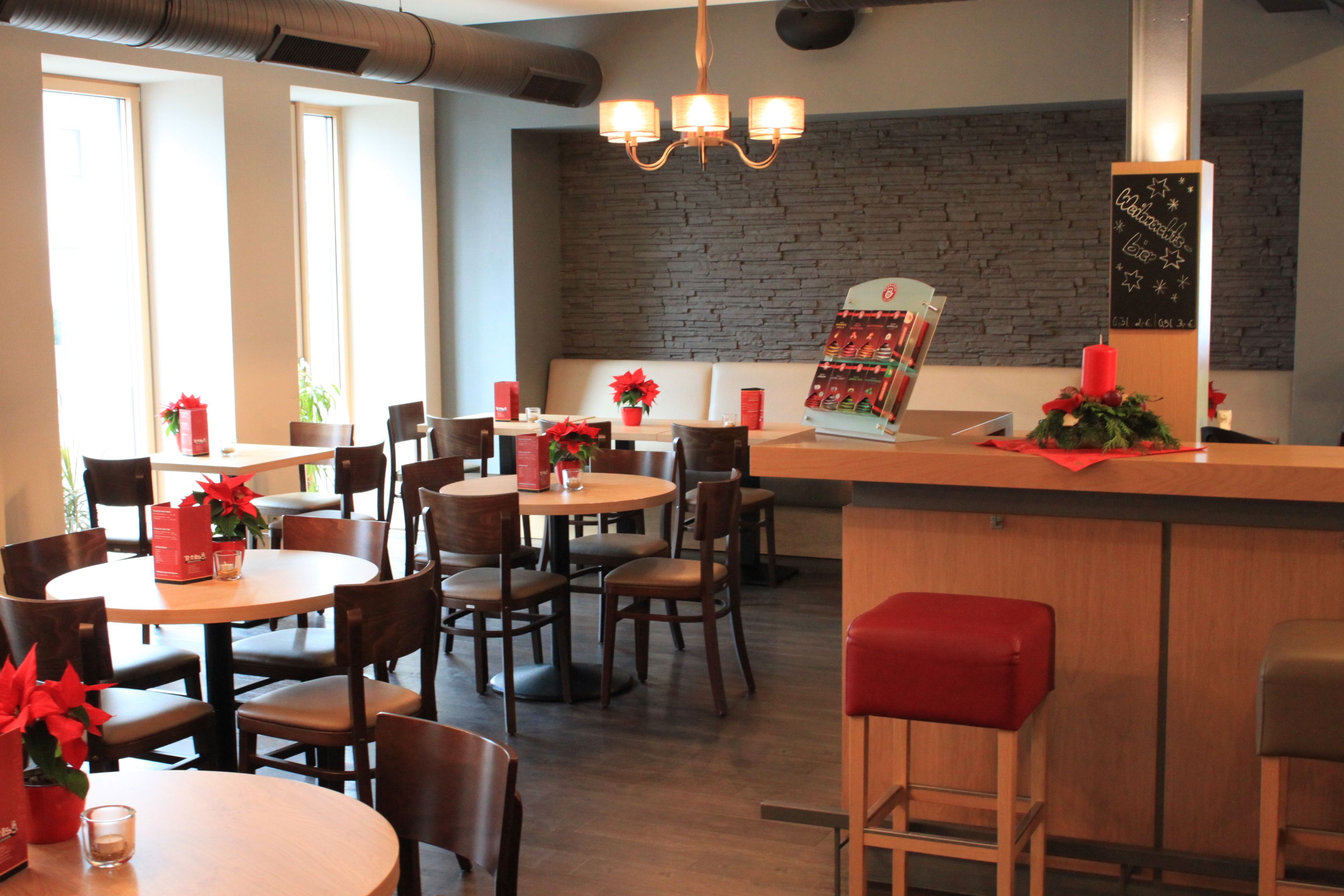 A restaurant with round tables and chairs, a bar area, and a chalkboard menu.