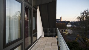 A modern building with large windows, a balcony, and construction equipment in the background. - Troll's Brauhaus Hotel (Medebach)