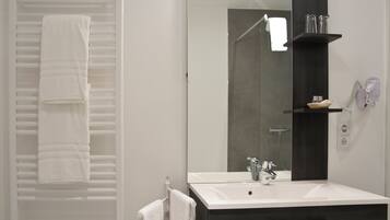 A modern bathroom with a white sink, a large mirror, and a towel rack with folded towels.