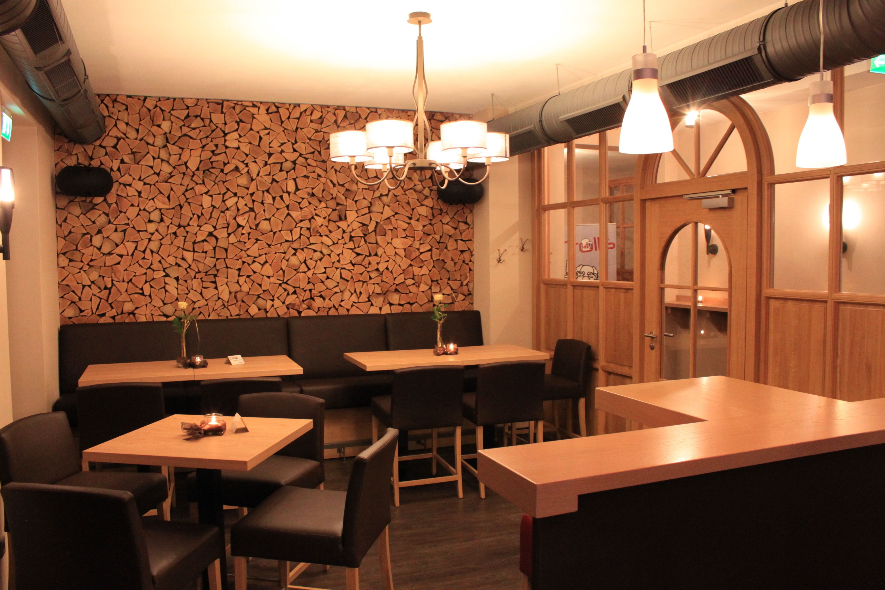 A restaurant with wooden walls, black chairs, and a central dining table.