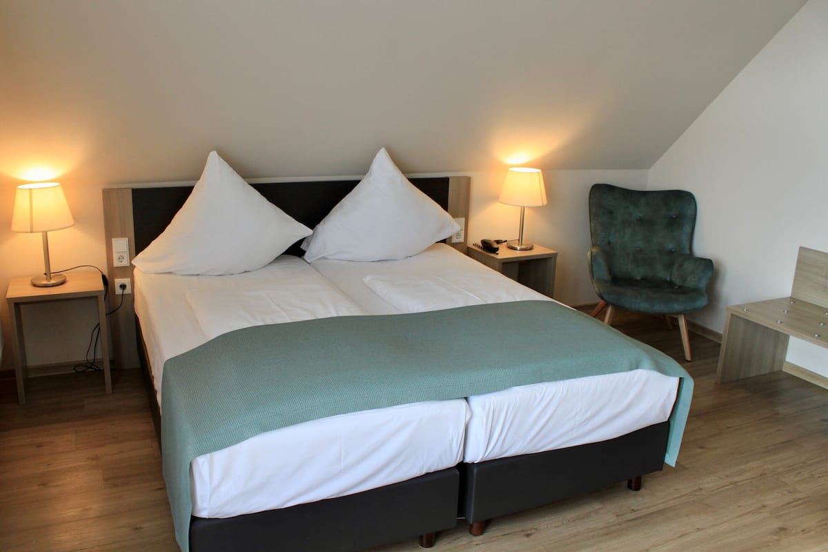A modern bedroom with a large bed, two bedside tables, a chair, and a desk.