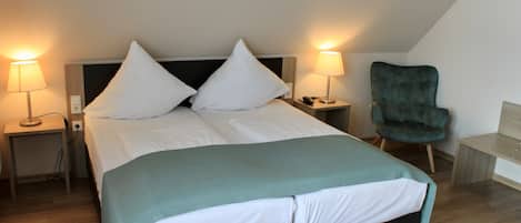 Un dormitorio moderno con una cama grande, dos mesitas de noche, una silla y un escritorio.