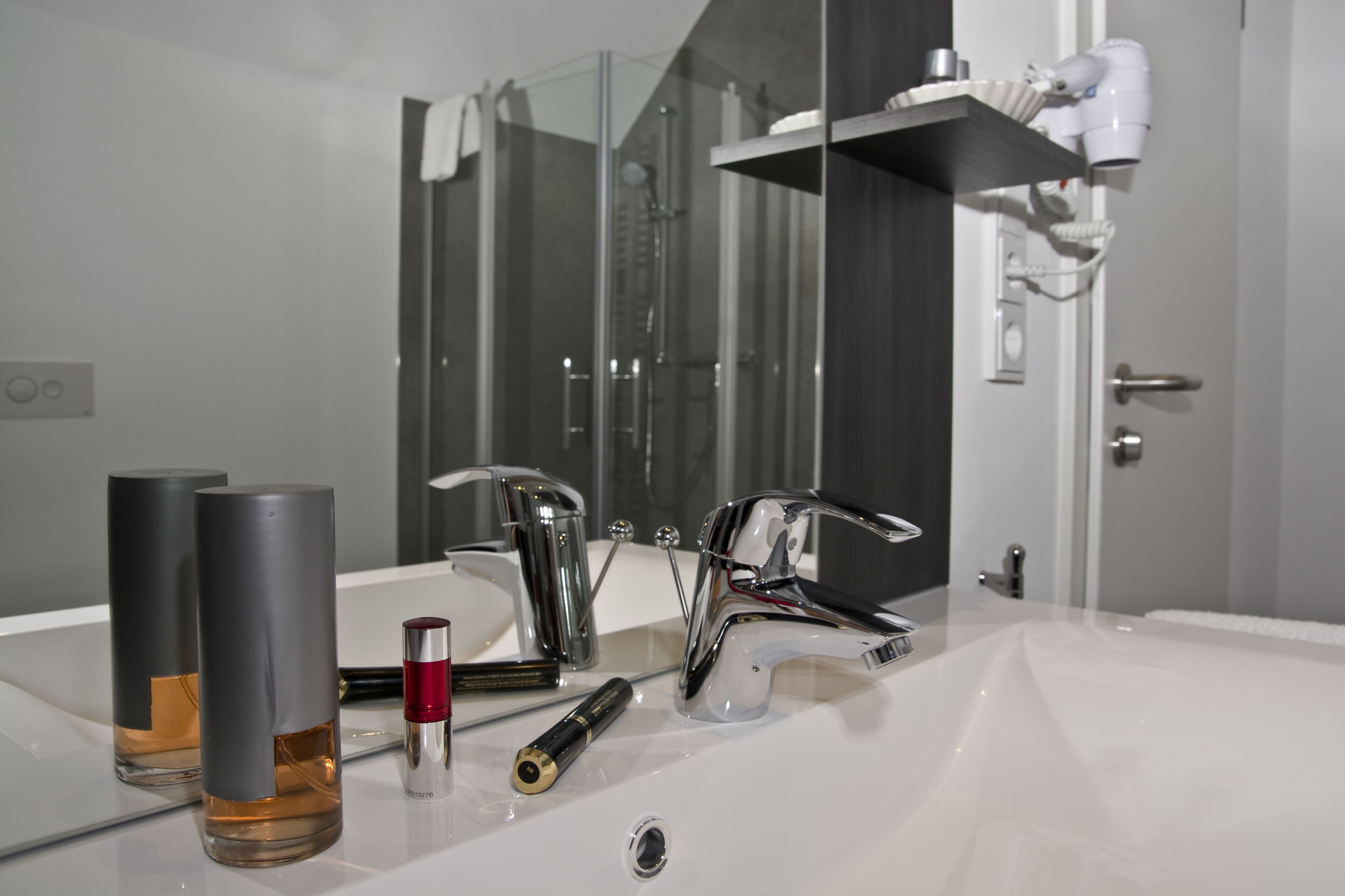 Un baño moderno con un espejo grande, accesorios cromados y dos recipientes cilíndricos sobre el lavabo.