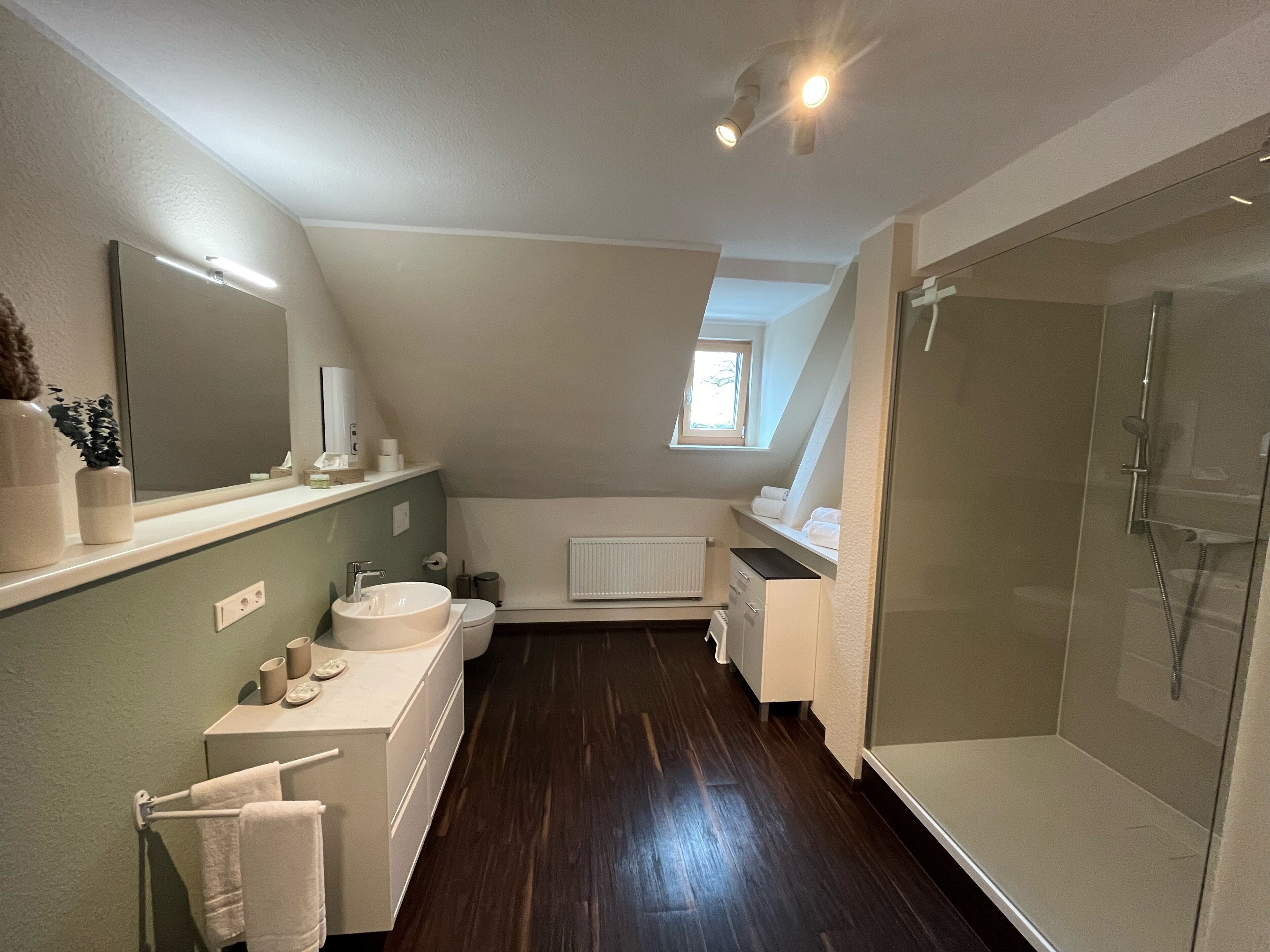 Un baño moderno con un espejo grande, un lavabo, un inodoro y una ducha.