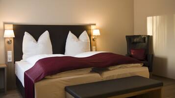 A hotel room with a large bed, two bedside lamps, a chair, and a bench.