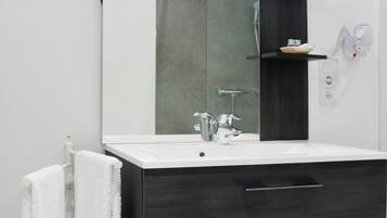 A modern bathroom with a large mirror, dark cabinetry, and a white countertop.