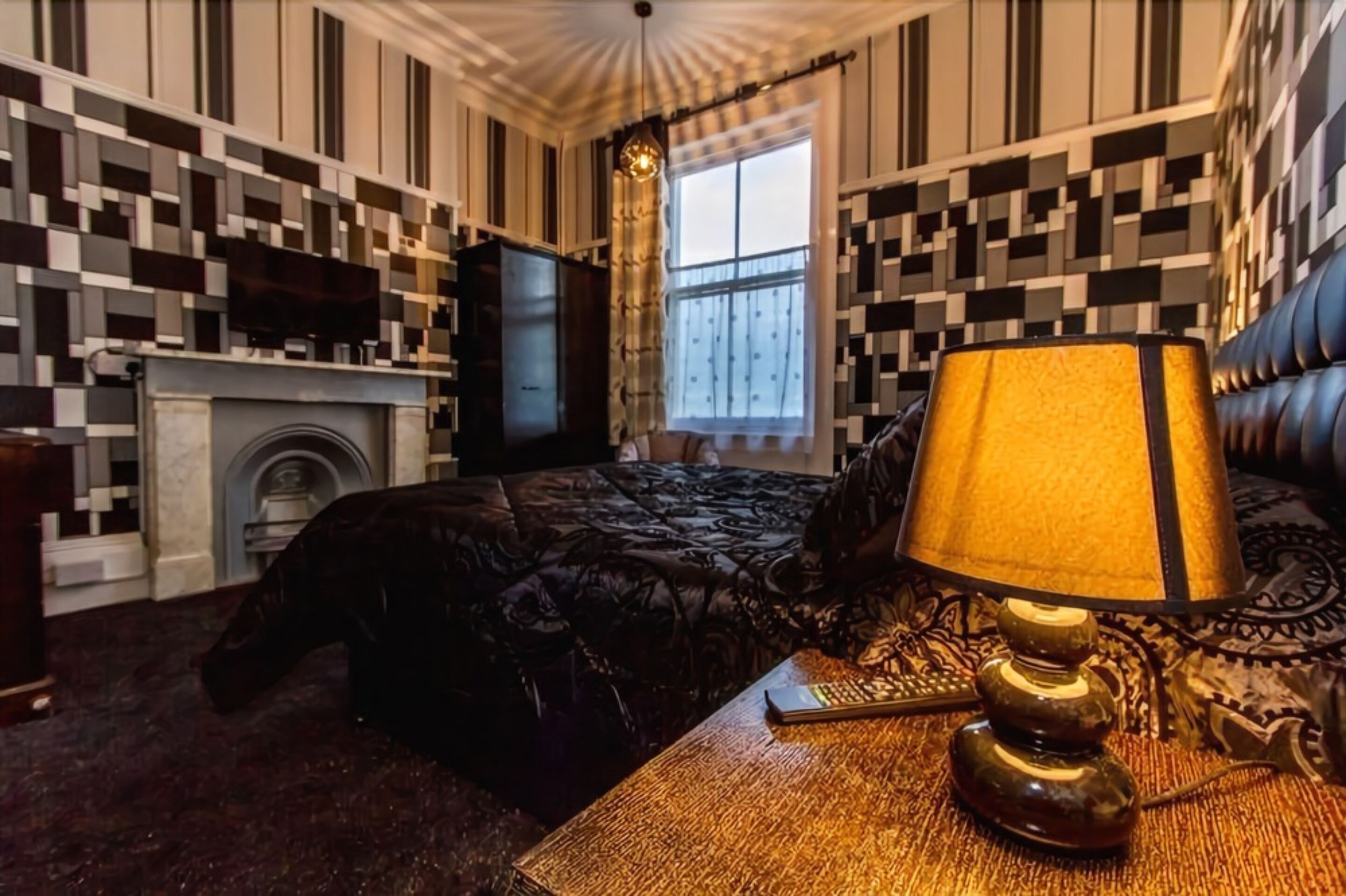 Una habitación con cama, televisión, chimenea y ventana con cortinas.