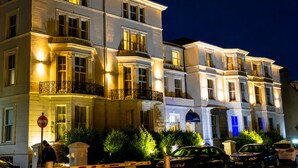 A multi-story building with balconies, a gated entrance, and parked cars. - The Carlton Hotel (Folkestone)