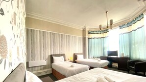 A hotel room with two single beds, a desk with a chair, a television, and a window with curtains. - The Carlton Hotel (Folkestone)