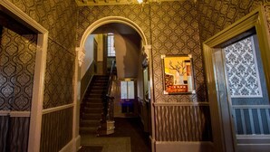 A hallway with patterned wallpaper, a staircase, and a framed artwork on the wall. - The Carlton Hotel (Folkestone)